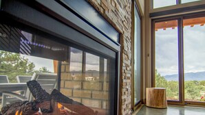 Un interior moderno con chimenea, un ventanal grande y vistas al exterior.