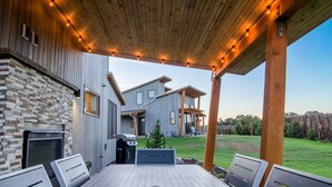Un patio cubierto con deck de madera, asador y zona de estar.
