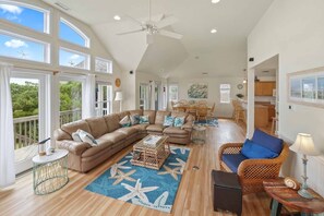 A spacious living room with a large sectional sofa, a blue starfish rug, and a ceiling fan. - Oceanview Down By The Sea! Home w/ Pool, Hot Tub, Elevator, Pier Passes, Game Rm (Rodanthe)