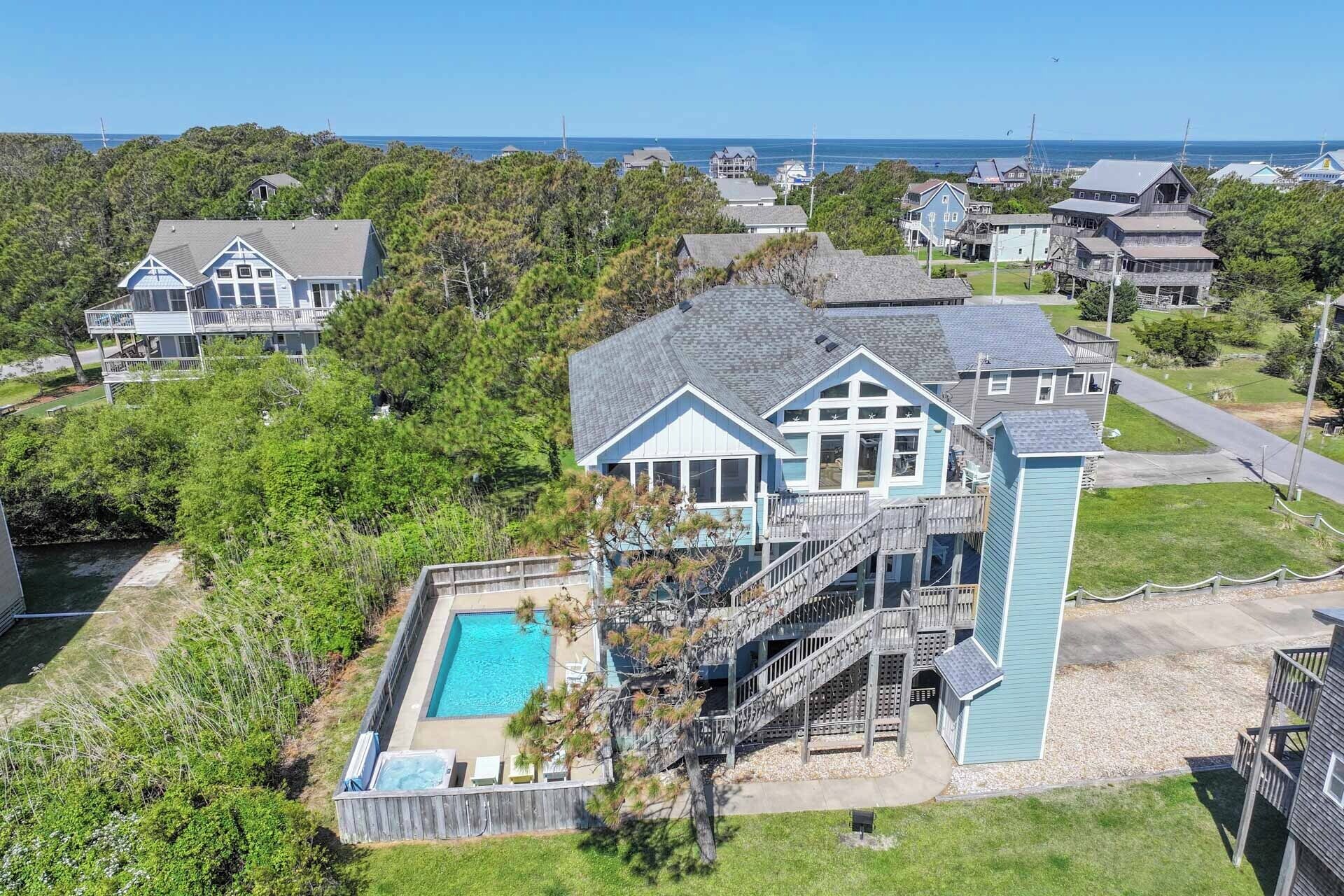A large house with a pool, a covered deck, and a staircase leading to a second floor.