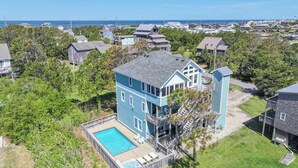 A two-story house with a large deck and a swimming pool.