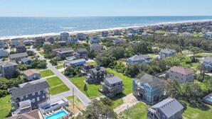 A coastal residential area with houses, a beach, and a clear sky.