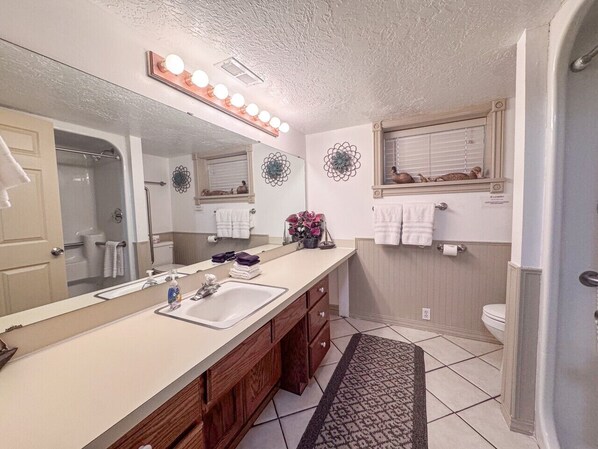 Une salle de bain avec un grand miroir, un meuble-lavabo et une douche.