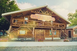 En rustik bygning i lodge-stil med et skilt der siger 'Pickleville Playhouse' og årstallet 1977.