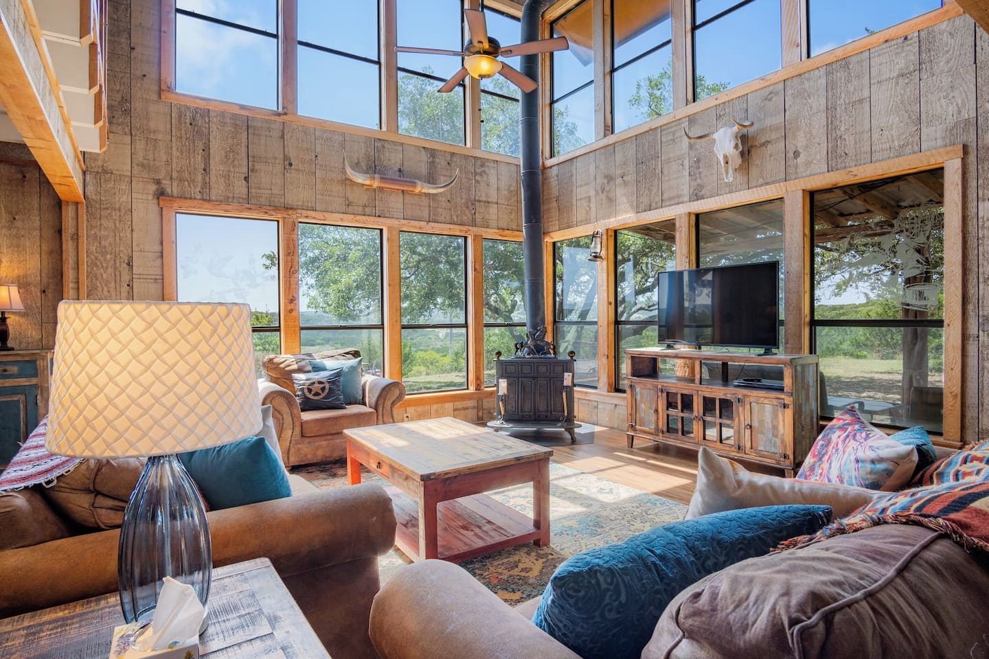 A spacious living room with a fireplace, comfortable seating, and large windows offering a view of the outdoors.