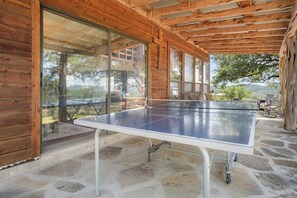 Ein Tischtennis-Tisch in einem überdachten Außenbereich mit Steinböden und Holzwänden.