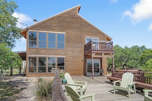 A wooden cabin with a deck, large windows, and a balcony.