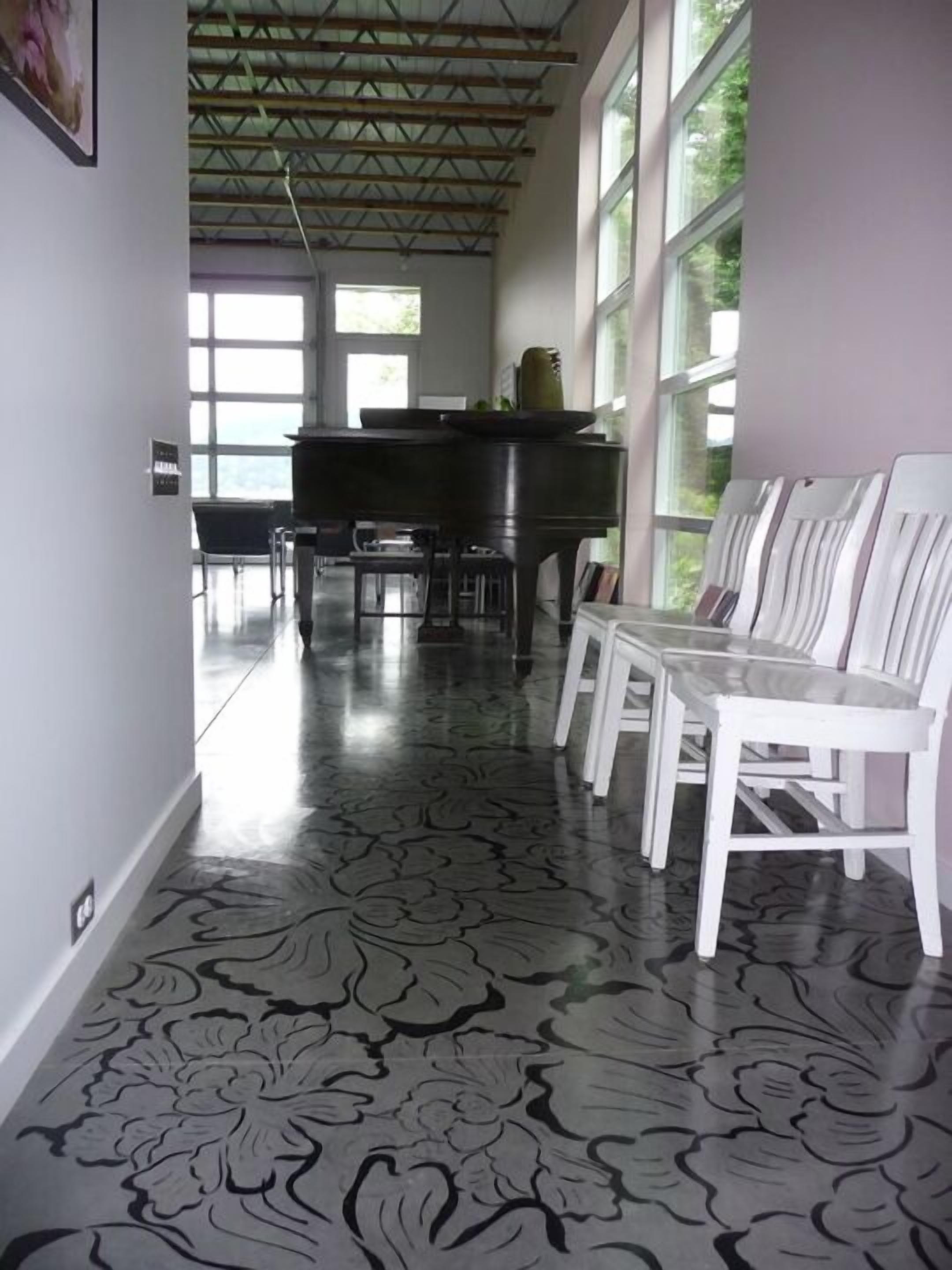 A hallway with a piano, white chairs, and patterned flooring.