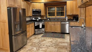 A kitchen with wooden cabinets, stainless steel appliances, a granite countertop, and a patterned rug. - Sugar Knoll Lodge / 3 Story, 5bdr, HOT TUB, East Zion, Bryce and Grand Canyon  (Orderville)