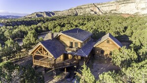 A wooden cabin with a balcony and a deck, surrounded by dense forest and mountains. - Sugar Knoll Lodge / 3 Story, 5bdr, HOT TUB, East Zion, Bryce and Grand Canyon  (Orderville)