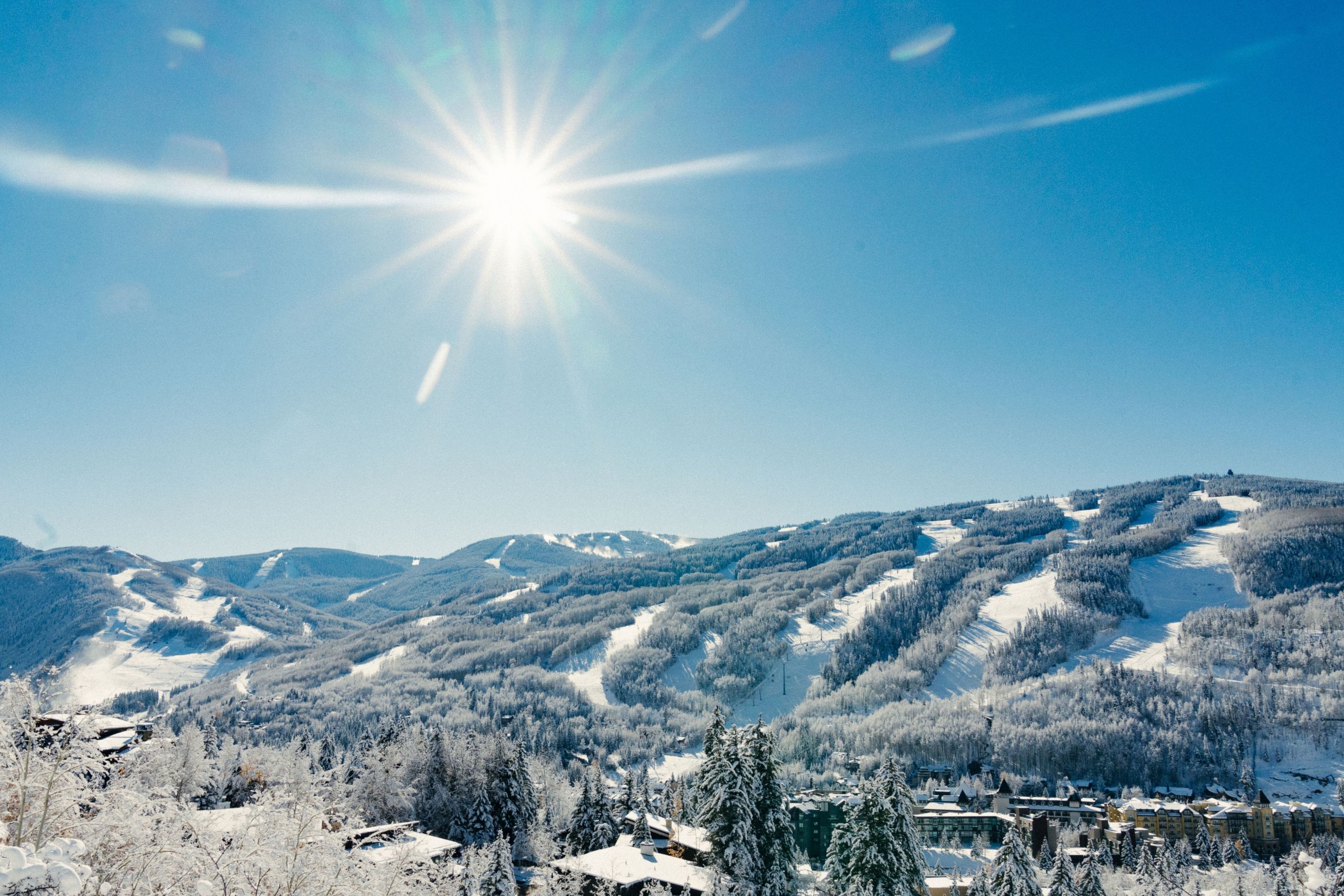 A snow-covered mountain landscape with a clear sky and a bright sun.