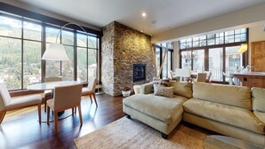 Un salón espacioso con chimenea de piedra, ventanas amplias y una zona de estar acogedora.