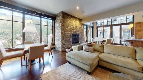 A spacious living room with a stone fireplace, large windows, and a cozy seating area.