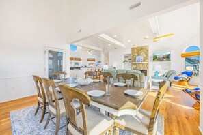 Un comedor amplio con una gran mesa de madera, varias sillas y vista a la cocina y al salón.
