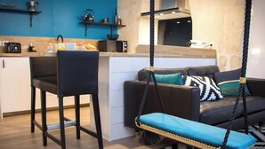 Een moderne keuken met een bar, een bank en een schommelstoel, en een vloerkleed met een patroon.