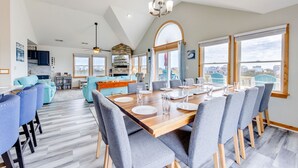 Une salle à manger spacieuse avec un haut plafond, une cheminée en pierre et de grandes fenêtres offrant une vue sur les environs.