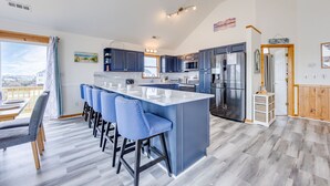 Une cuisine moderne dotée d’un îlot central, de tabourets de bar et offrant une vue sur l’extérieur.