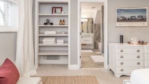 A neatly organized bedroom with a closet, a bedside table, and a framed picture on the wall. - Newly Renovated Mid-Century Home (Newtown Square)