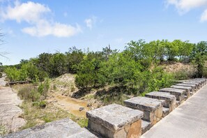 Un muro de hormigón con escalones que conducen a una zona cubierta de césped con un pequeño arroyo.