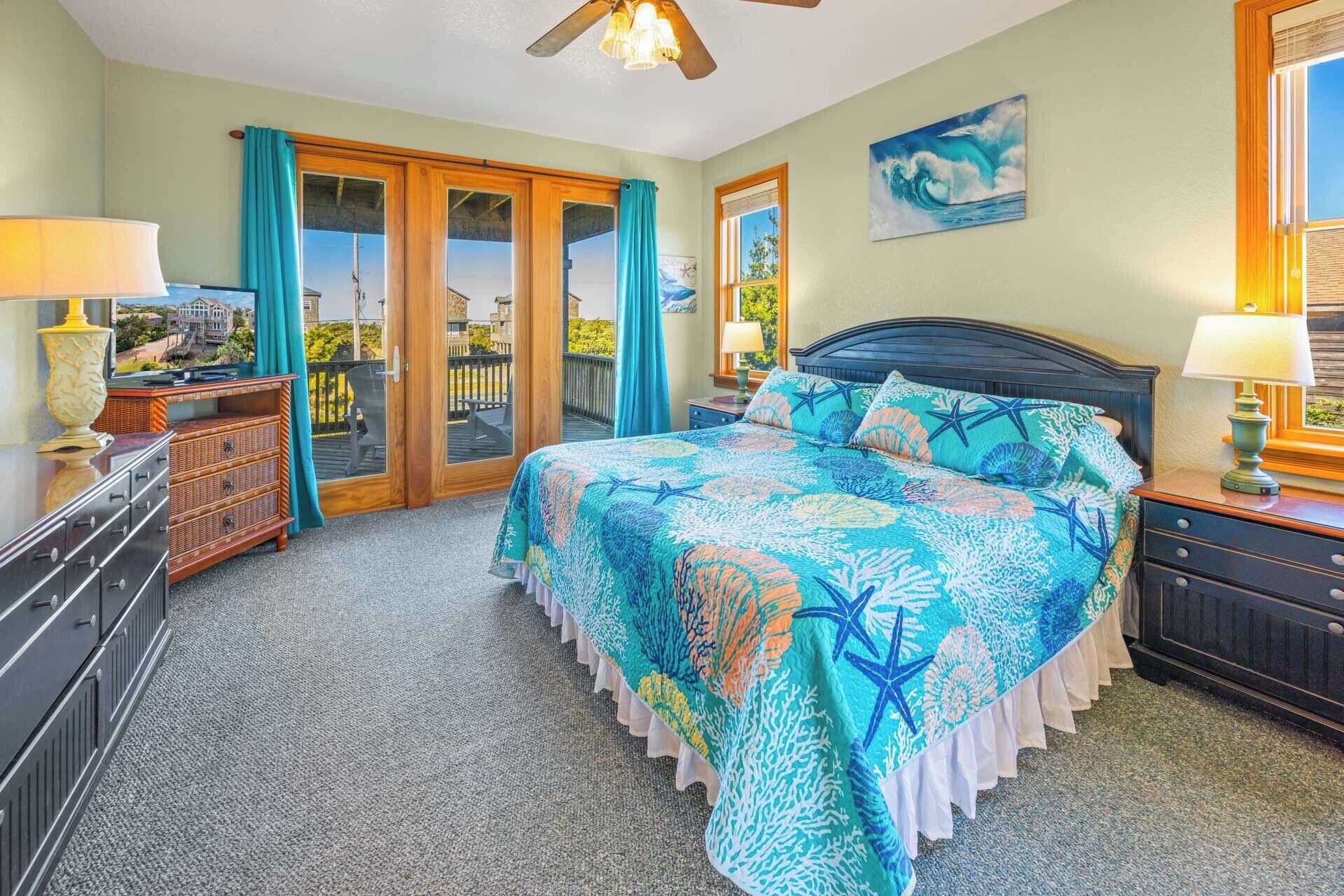 A bedroom with a large bed, a dresser, a nightstand, and a ceiling fan.