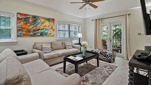 A living room with a sofa, coffee table, and artwork on the wall. - Spacious 3 BR Townhouse w/ Infinity Pool Views (Nassau)
