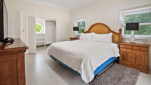 A bedroom with a bed, wooden nightstands, a ceiling fan, a television, and a window with blinds. - Spacious 3 BR Townhouse w/ Infinity Pool Views (Nassau)