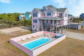 A two-story house with a swimming pool, outdoor seating, and a deck.