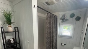 Un bagno con doccia, lavandino, porta asciugamani e una pianta in vaso.