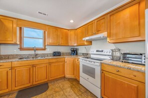 A kitchen with wooden cabinets, a built-in oven, a stovetop, and a window.