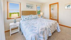 A bedroom with a bed, two bedside tables, a nightstand, a window with a view, and a door.