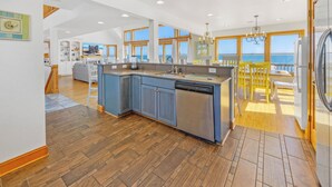 Een moderne keuken met een groot eiland, houten vloeren en uitzicht op de oceaan.