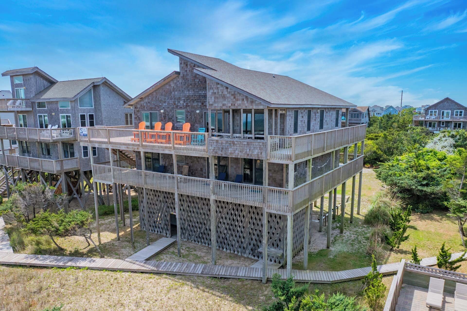 A multi-story wooden house with a balcony and outdoor seating area.