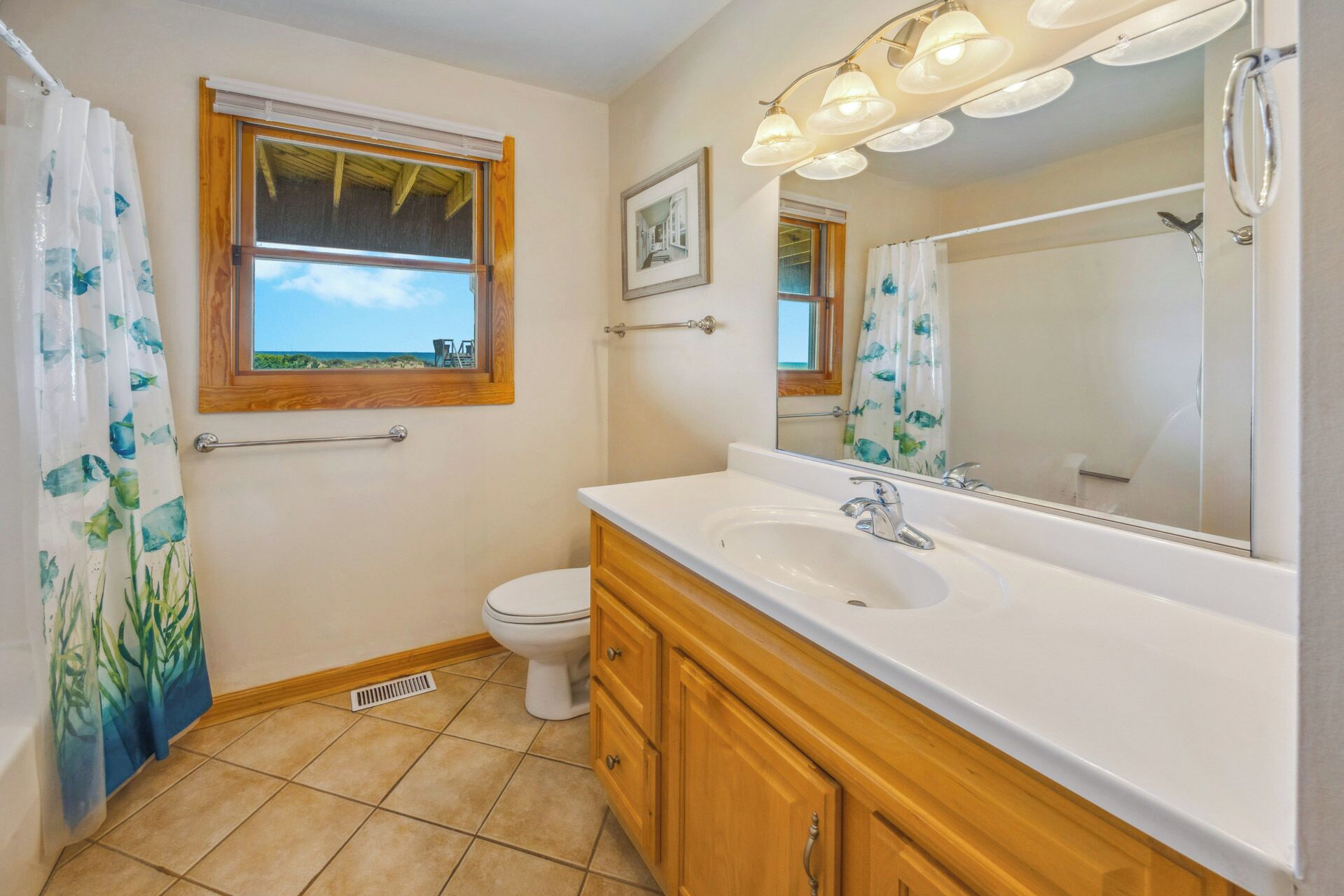 Une salle de bain avec une grande fenêtre, un lavabo, des toilettes et un miroir.
