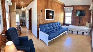 A cozy room with a blue sofa, a white armchair, and a bed with a striped blanket. - Diane Cottage, York Manor, Short Sands Beach (York)