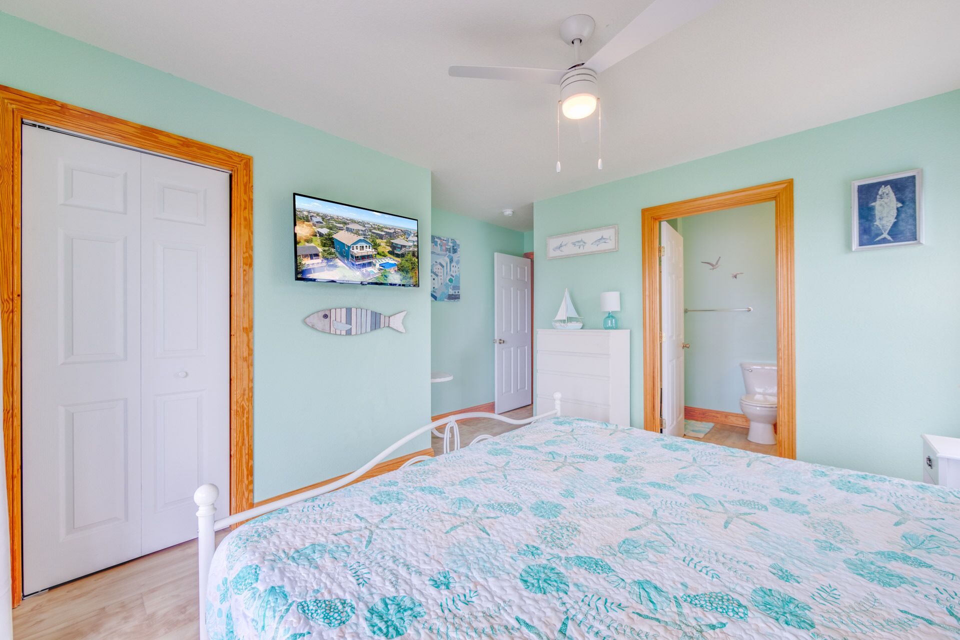 A bedroom with a bed, a television on the wall, and a door leading to another room.
