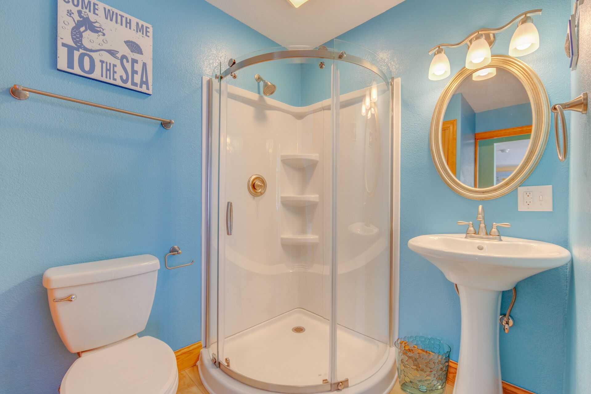 Un baño con ducha de vidrio, lavamanos blanco y un inodoro.