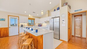Una cocina moderna con armarios blancos, un refrigerador de acero inoxidable y una isla de madera con taburetes.