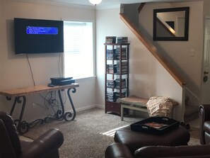 Relax in this inviting living room with a flat-screen TV, comfortable sofa, and cozy armchair.