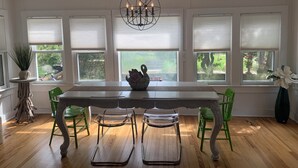 A dining area with a large table, green chairs, and a chandelier. - Beautiful Ocean Park Family Vacation Rental (Ocean Bay Park)
