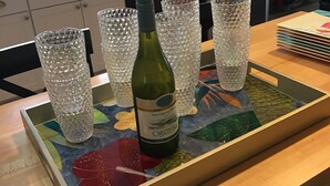 A kitchen counter with a bottle of wine, several crystal glasses, and a colorful tray. - Beautiful Ocean Park Family Vacation Rental (Ocean Bay Park)