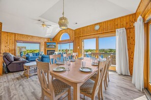 A wooden interior with a dining area, sofas, and a view of the outdoors.