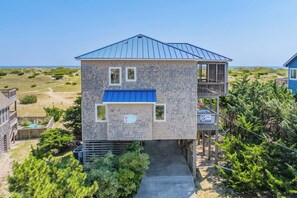 A two-story building with a blue roof, a balcony, and a small deck area. - Oceanfront Dog Friendly Home in Salvo w/ Private Pool, Hot Tub, and Game Room (Salvo)