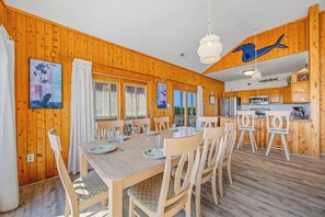 A wooden-paneled room with a dining table, chairs, and a kitchen area. - Oceanfront Dog Friendly Home in Salvo w/ Private Pool, Hot Tub, and Game Room (Salvo)