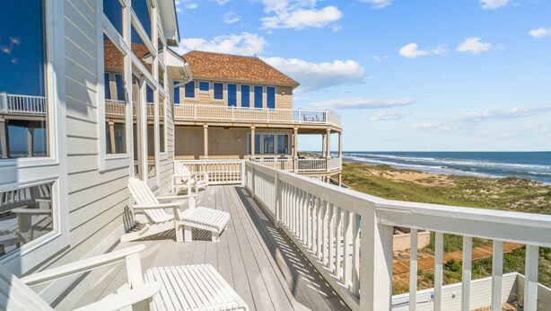 A beachfront property with a wooden deck, white railings, and multiple levels with balconies. - Premier Oceanfront Dog Friendly w/ Pool, Elevator, Hot Tub, Theater & Game Rooms (Hatteras)
