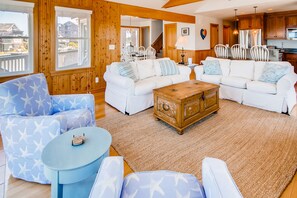 Ein geräumiges Wohnzimmer mit einem großen weißen Sofa, einem blauen Sessel und einem Holztisch.