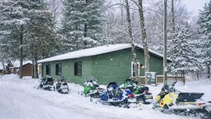 A snow-covered cabin with snowmobiles parked in front. - Cabin w/ gas fireplace, playground& AuTrain Lk Access (AuTrain)