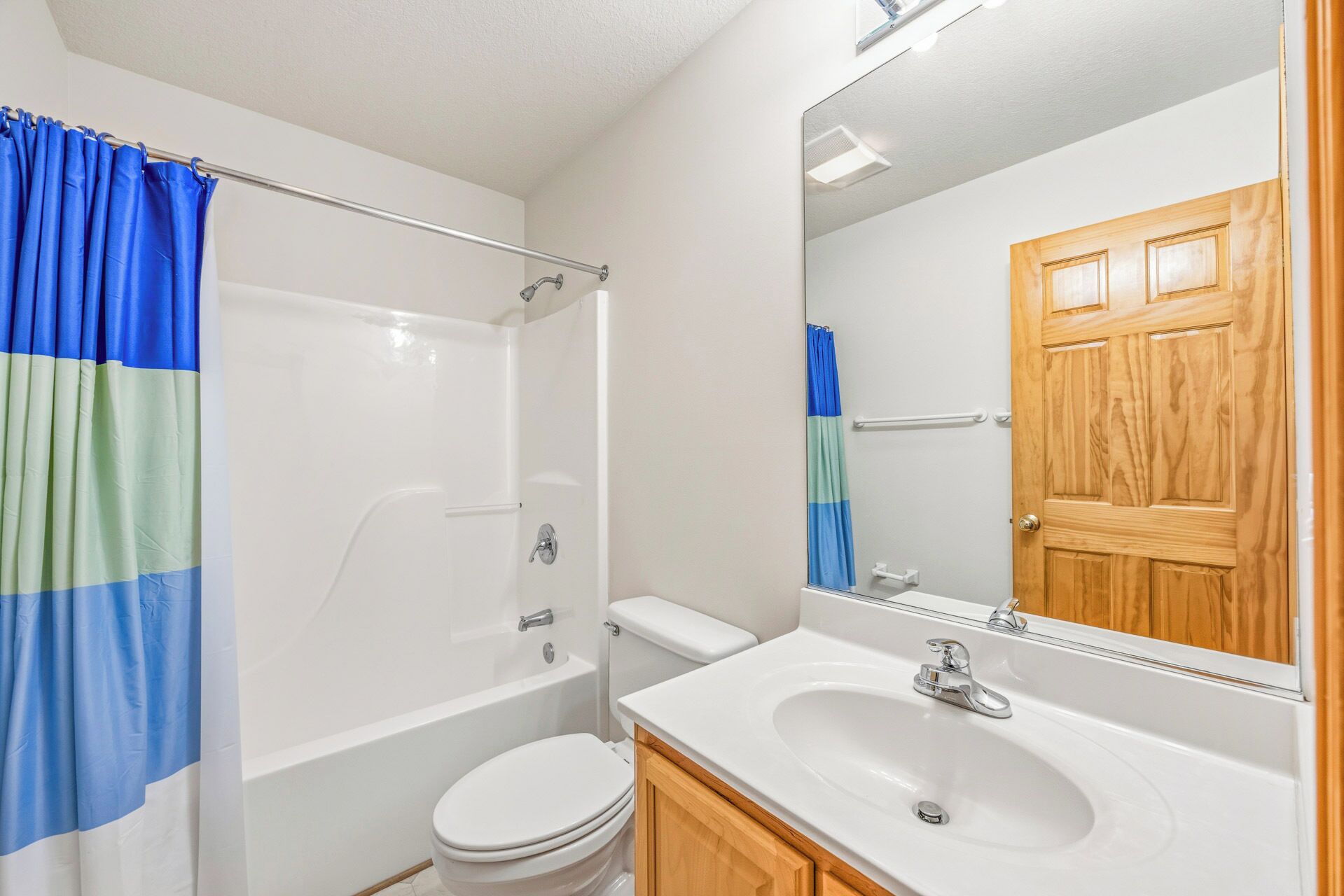 A bathroom with a bathtub, toilet, sink, and a wooden door.