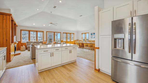 A spacious kitchen with wooden flooring, a large island, white cabinetry, and a stainless steel refrigerator. - Semi-Oceanfront Dog Friendly Home w/ Pool, Hot Tub, Renovated Kitchen, Game Room (Hatteras)
