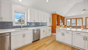 A modern kitchen with white cabinets, a dishwasher, and a wooden accent wall. - Semi-Oceanfront Dog Friendly Home w/ Pool, Hot Tub, Renovated Kitchen, Game Room (Hatteras)