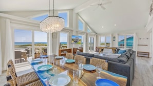 A spacious living area with a large dining table, comfortable seating, and a view of the ocean. - Oceanfront Dog Friendly Home with Private Pool, Hot Tub, Direct Beach Access (Avon)